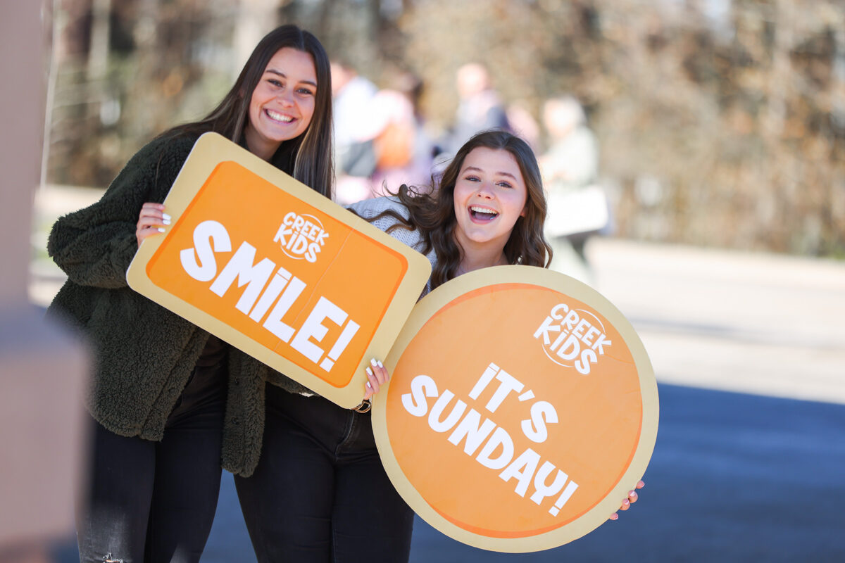 Creek Kids Staff Smiling and holding signs